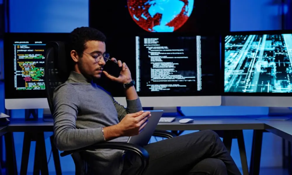 Man holding a phone and looking at a tablet for proactive IT management.