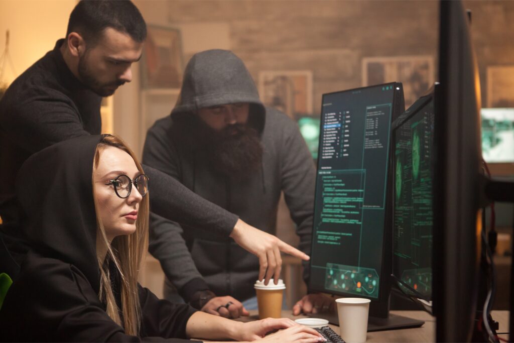 Three hackers executing cybersecurity threats, making it more important than ever to know how to protect against cyber threats and take steps to improve your cybersecurity.