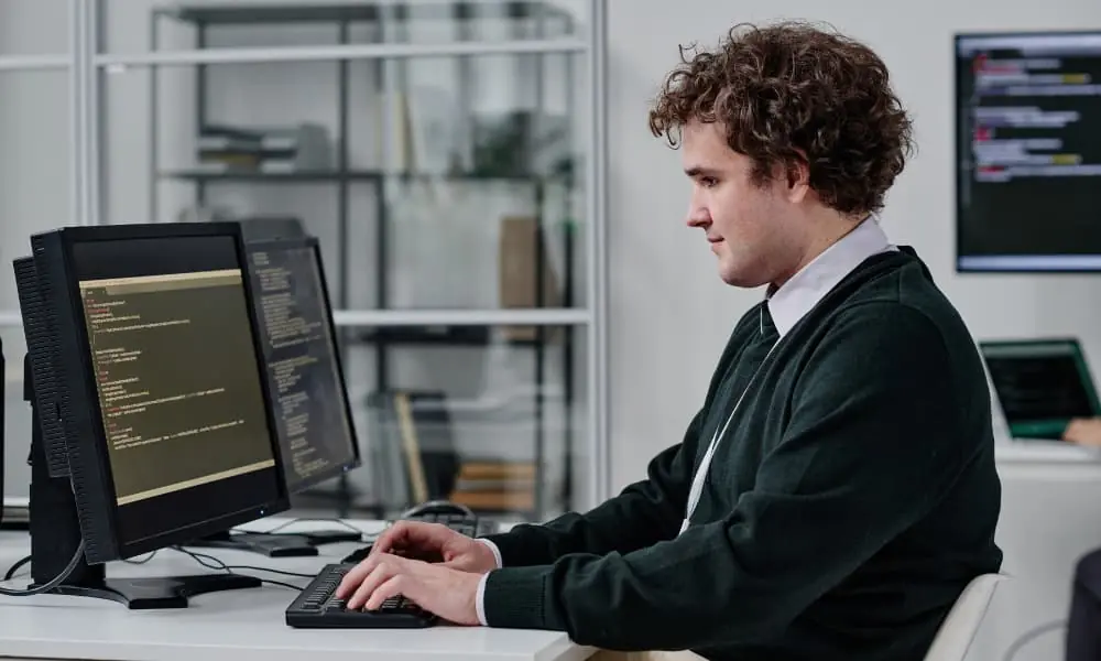 An employee uses remote I.T. support at his desk while working to proactively solve a problem.