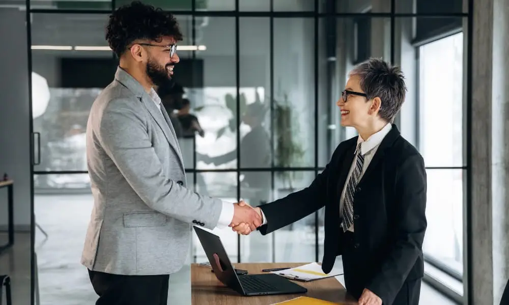 An SMB owner shakes hands with an outsourced network management services company’s representative.
