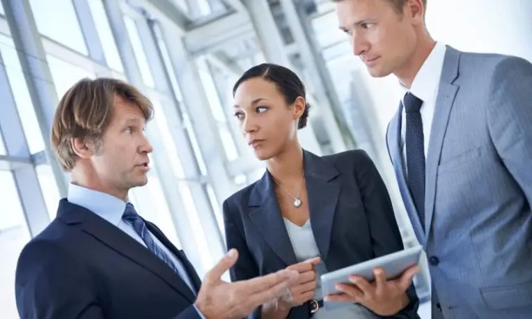 Three business people discussing, “how much do managed I.T. services cost?”