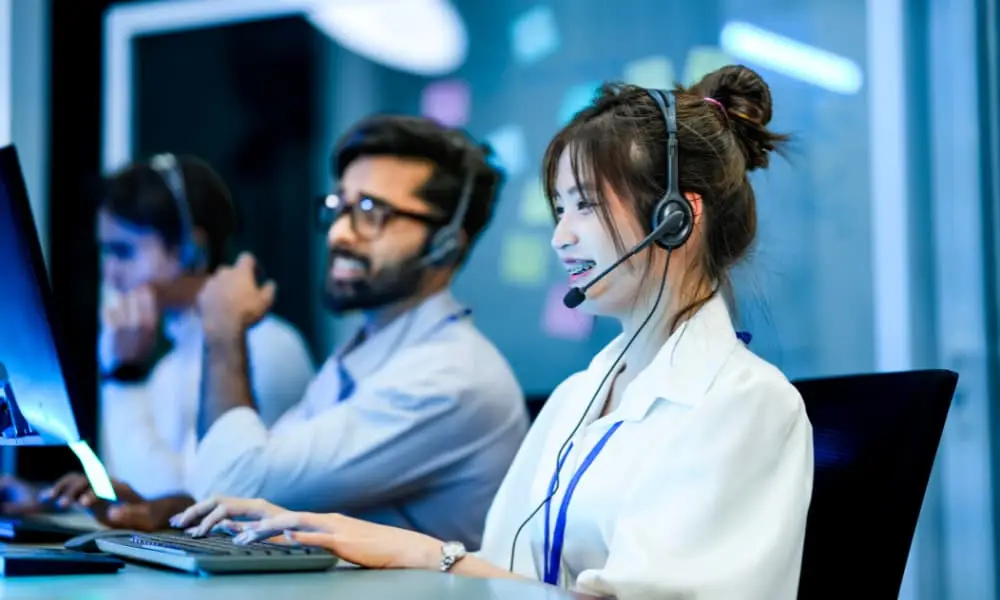Technical support specialists working together at computer monitors.